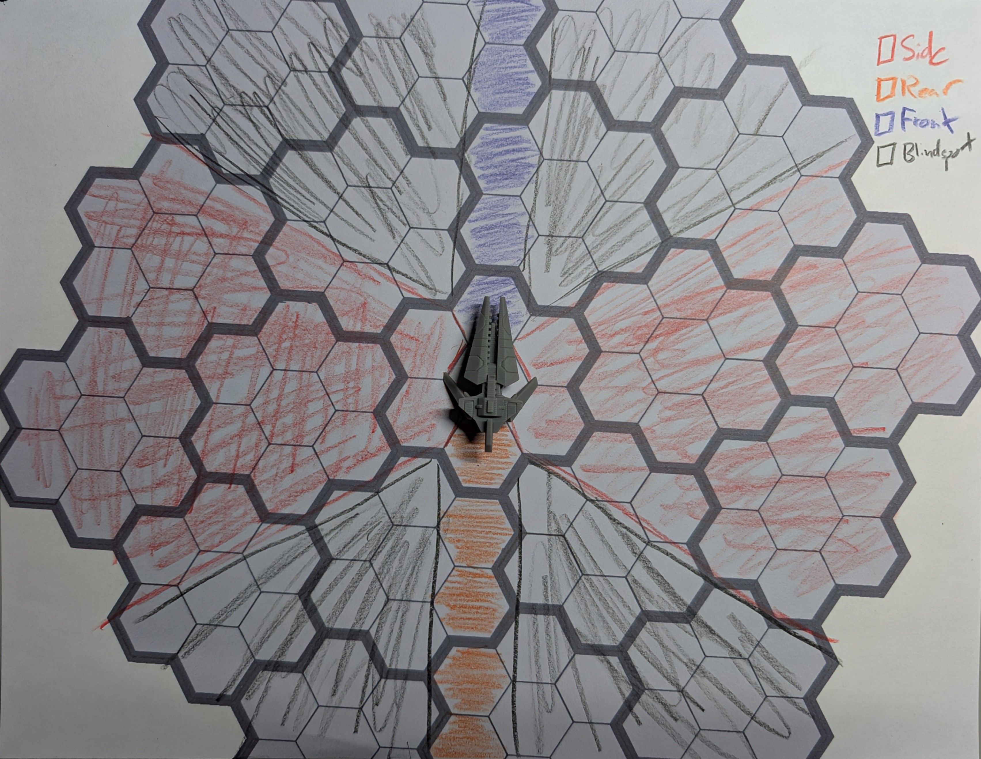 A top down view of a hex grid printed on a piece of paper. A spaceship mini sits on a hex at the center, and from each of face of the hex, an area has been colored in with colored pencils to represent the different attack cones of the the spaceship